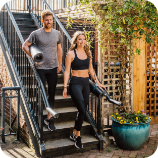 A photo of two people heading down stairs after a yoga class, wearing stylish Bracelayer KS1 compression leggings with knee support.