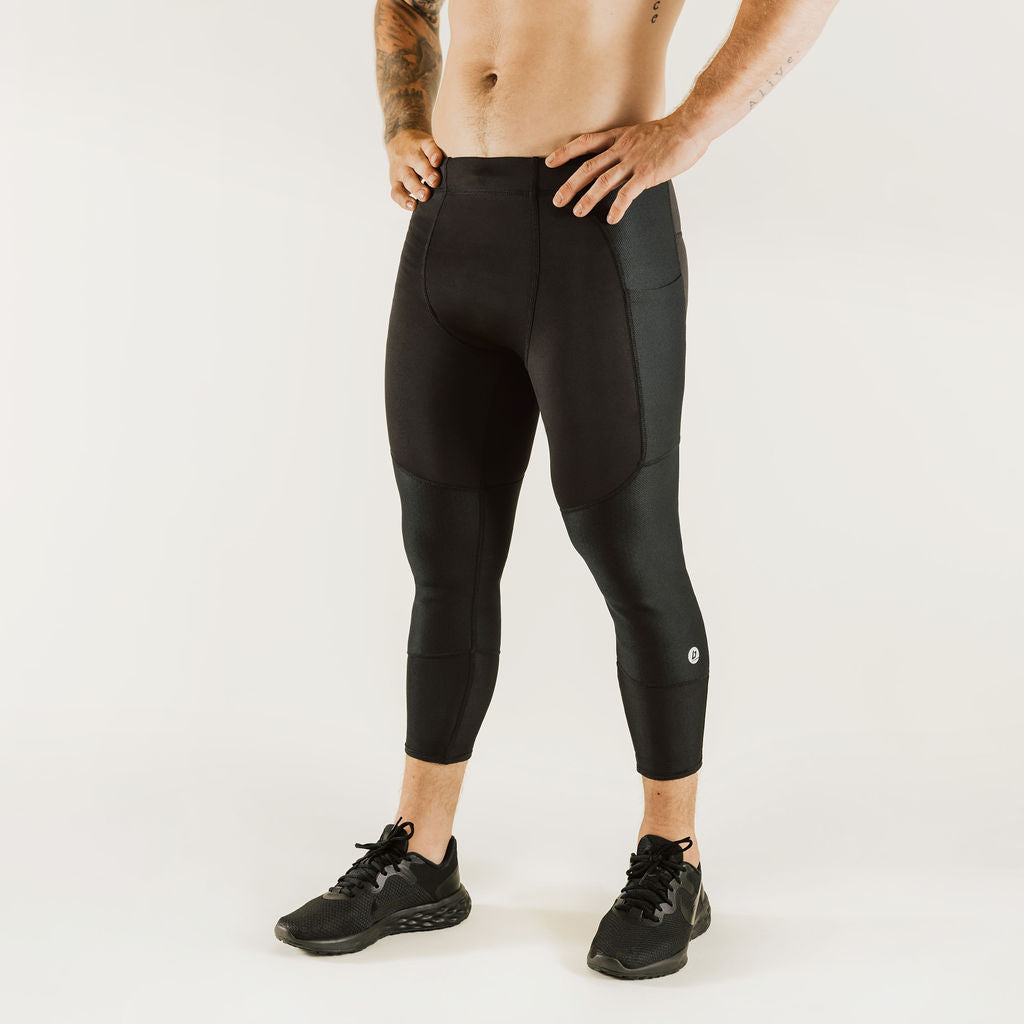Men's low-rise black compression pants, 7/8 length, front view with logo marks
